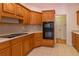 Traditional-style kitchen with wooden cabinets, tile flooring, and modern black appliances at 5581 Fox Glove Ct, Douglasville, GA 30135