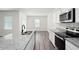 Bright kitchen featuring granite countertops, stainless appliances, an island with a sink, and wood-look flooring at 7301 Cranleigh St, Covington, GA 30014