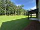 Spacious backyard featuring a covered patio and a large, grassy area surrounded by trees at 2571 Se Ebenezer Rd, Conyers, GA 30094