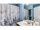 Well-lit bathroom with a single vanity, mirror, and a shower with a floral-patterned curtain at 1810 Stardust Trl, Cumming, GA 30040