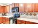 Kitchen features cherry wood cabinets, black appliances, and tile backsplash at 1810 Stardust Trl, Cumming, GA 30040