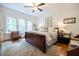 Bright bedroom with a dark sleigh bed frame, ceiling fan, and a seating area with windows at 401 Emory Ne Dr, Atlanta, GA 30307