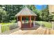 Wooden gazebo with a peaked roof, white railings, and ample space for outdoor seating at 5300 Haynes Creek Dr, Loganville, GA 30052