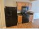 Kitchen area features a black refrigerator and gas range, wood cabinets, and wood flooring at 1865 Ellison Lakes Nw Ct # 21, Kennesaw, GA 30152