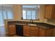 View of kitchen with wood cabinets, stainless steel sink, and a view of the living room at 1865 Ellison Lakes Nw Ct # 21, Kennesaw, GA 30152