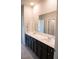 Bathroom with double sink vanity, dark cabinets, neutral tile, and a large mirror reflecting bright lighting at 3739 In Bloom Way, Auburn, GA 30011