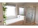 Bright bathroom featuring a soaking tub and a separate glass-enclosed shower at 3739 In Bloom Way, Auburn, GA 30011