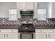 Modern kitchen with mosaic backsplash, white cabinets, and a black gas cooktop at 3772 Sunbridge Dr, Snellville, GA 30039
