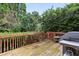Wooden deck area with grill and fenced in backyard with mature landscaping at 4944 Dovecote Trl, Suwanee, GA 30024