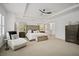 Spacious main bedroom with a tray ceiling, accent chair, ceiling fan, tufted headboard, and ensuite bathroom at 1059 Rockford Township Sw Dr, Marietta, GA 30064