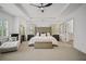 Spacious main bedroom features a tray ceiling, ceiling fan, sitting area, tufted headboard, and ensuite bathroom at 1059 Rockford Township Sw Dr, Marietta, GA 30064