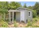 Quaint backyard shed featuring a covered entry, painted exterior, and pet door, surrounded by lush greenery at 4102 Barr Cir, Tucker, GA 30084