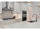 Modern kitchen boasts white cabinets, stainless steel appliances, and a sleek range hood over the cooktop at 4960 Iris St, Cumming, GA 30040