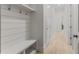 Mud room with bench, hooks, storage shelves, and neutral paint leads into hallway with hardwood flooring at 4960 Iris St, Cumming, GA 30040