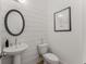 This powder room features white shiplap walls and a pedestal sink with a rounded black mirror at 4960 Iris St, Cumming, GA 30040