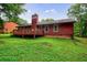 Back exterior view of home with a wood deck, showing the backyard with a lush green lawn and trees at 335 Whisper Way, Dacula, GA 30019