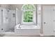 Bright bathroom featuring a tub, a glass-enclosed shower, and a large arched window at 992 Marbury Sw Ct, Marietta, GA 30064