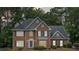 Charming brick two-story home with a blue front door, a manicured lawn, mature trees, and dark shutters at 992 Marbury Sw Ct, Marietta, GA 30064