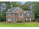 Charming brick two-story home with a blue front door, a manicured lawn, mature trees, and dark shutters at 992 Marbury Sw Ct, Marietta, GA 30064