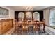 Formal dining room with wooden table, decorative rug, and a series of arched mirrors reflecting the chandelier at 5105 Vernon Oaks Dr, Dunwoody, GA 30338