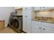 Convenient laundry room features modern washer and dryer with white cabinets and granite countertops at 650 Chestatee Creek Nw Dr, Acworth, GA 30101