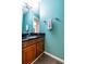Stylish half bathroom featuring bold teal walls, dark vanity with a marble countertop, and a decorative mirror at 104 Powell Cv, Decatur, GA 30030