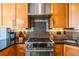 Close-up of the modern kitchen features a stainless steel range, wood cabinetry, and mosaic tile backsplash at 104 Powell Cv, Decatur, GA 30030