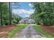 Elegant home nestled among mature trees and greenery with a paved driveway at 1213 Grande Vw, Loganville, GA 30052