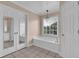 Relaxing bathroom with a soaking tub by a bright window and mirrored closet doors at 7325 Brookwood Way, Cumming, GA 30041