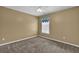 A tan-painted bedroom featuring a window, a ceiling fan, and neutral carpeting at 7325 Brookwood Way, Cumming, GA 30041