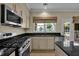 Updated kitchen with stainless appliances, neutral cabinets, black countertops and natural light at 7325 Brookwood Way, Cumming, GA 30041