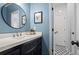 This half bath features a blue accent wall, unique flooring, a framed mirror and updated lighting at 605 Linkside Hollow, Alpharetta, GA 30005