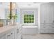 Bright bathroom with white cabinetry, soaking tub, and a large window overlooking the backyard at 605 Linkside Hollow, Alpharetta, GA 30005