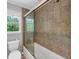 Tiled bathroom featuring glass sliding shower doors over a tub with a toilet and window to the left at 4157 Berkeley Nw Lndg, Kennesaw, GA 30144