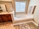 Bright bathroom featuring a soaking tub with a window and travertine-style floor tiles at 4978 Arborview Pkwy, Acworth, GA 30101