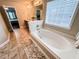 Bright bathroom featuring a soaking tub with a window and travertine-style floor tiles at 4978 Arborview Pkwy, Acworth, GA 30101