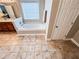 A luxurious bathroom featuring a soaking tub with a window and travertine-style floor tiles at 4978 Arborview Pkwy, Acworth, GA 30101