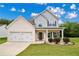 Charming two-story home featuring a two-car garage, landscaped yard, and inviting front porch under a bright blue sky at 176 Windy Cir, Mcdonough, GA 30253