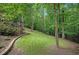 Sloping backyard with a well-maintained lawn, bordered by mature trees and a deck at 1170 Spring Oak Way, Cumming, GA 30041