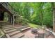 Brick patio with fire pit, seating, and stairs to deck overlooking wooded backyard at 1170 Spring Oak Way, Cumming, GA 30041