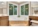 Bright bathroom featuring tiled tub and large windows overlooking a wooded area at 1170 Spring Oak Way, Cumming, GA 30041