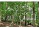 Exterior view of a charming home nestled among lush trees with a welcoming front porch, offering a serene setting at 1170 Spring Oak Way, Cumming, GA 30041
