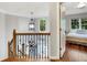 Hallway landing with decorative railing leading to a bedroom with light-filled windows and cozy decor at 1170 Spring Oak Way, Cumming, GA 30041