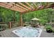 Outdoor hot tub on wooden deck with dining table and wooded view in the background at 1170 Spring Oak Way, Cumming, GA 30041