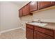 Laundry room with brown cabinets, tile flooring, and granite countertop at 430 La Perla Dr, Sugar Hill, GA 30518