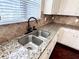 Close up of the double sink with granite countertops, tile backsplash, and a view to the outdoors at 958 Nevis Way, Mcdonough, GA 30253