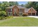 Beautiful two-story brick home with mature trees, manicured lawn and three-car garage at 1835 Redbourne Dr, Atlanta, GA 30350