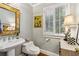 Stylish powder room with pedestal sink, decorative mirror, and natural light from shuttered window at 1835 Redbourne Dr, Atlanta, GA 30350