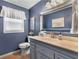 Elegant powder room featuring blue walls, custom vanity, and framed mirror, providing a stylish and functional space at 4875 Rivercliff Sw Trce, Lilburn, GA 30047