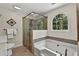 Modern bathroom with a glass-enclosed shower, soaking tub, and arched window offering natural light at 4875 Rivercliff Sw Trce, Lilburn, GA 30047